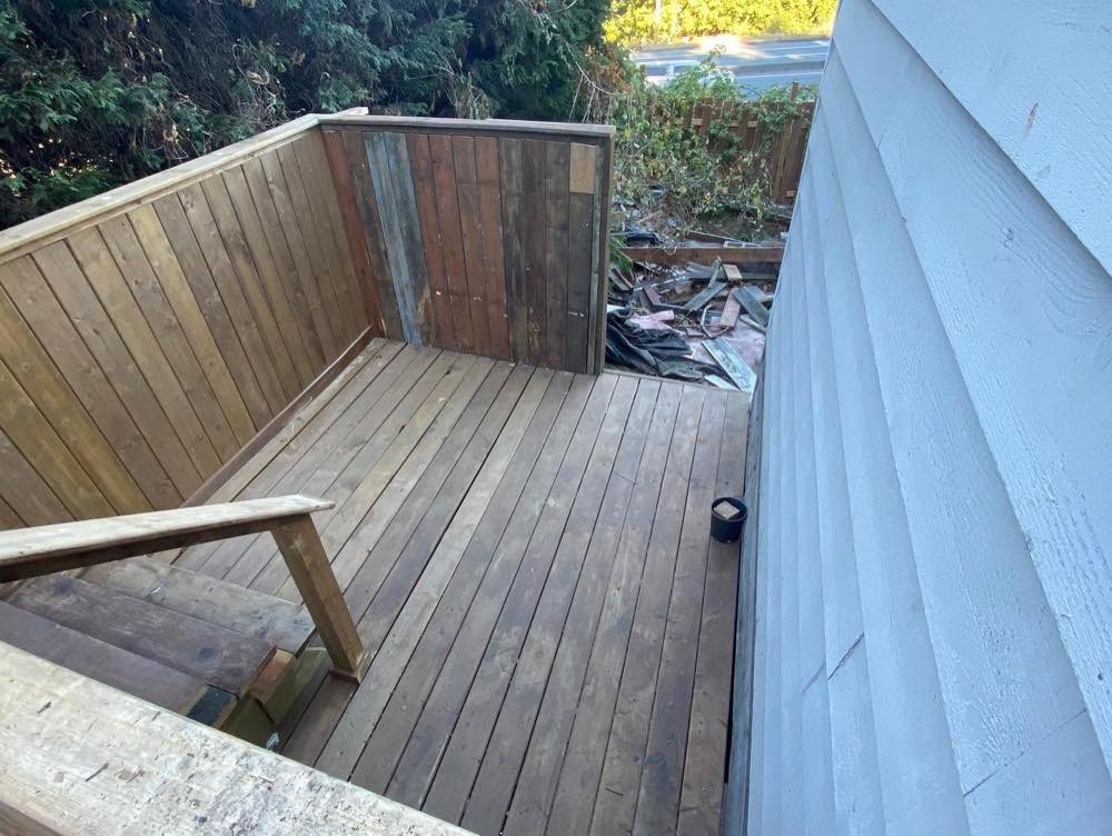 After: the rebuilt deck with new stained decking, privacy screen walls, and new stairs and handrail